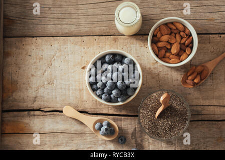 Mirtilli freschi, mandorla e semi di Chia con il latte sulla tavola di legno. Ideale colazione sana nozione. Foto Stock