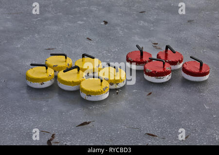 Il rosso e il giallo metallo pietre di curling su ghiaccio, il lago Malaren, Svezia e Scandinavia Foto Stock