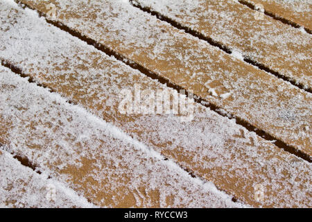 Close up vista astratta di un colore marrone deck di cedro pavimento coperto di fresco con neve shoveled Foto Stock