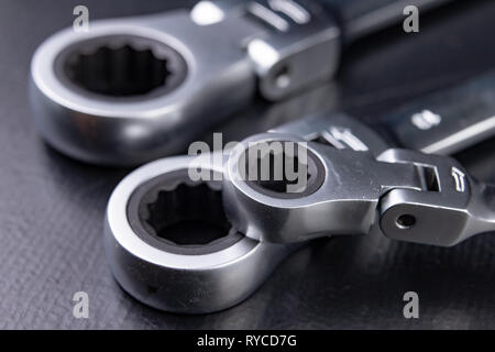 Nuovo cromato anello chiave con chiusura a scatto. Accessori per un meccanico su una tabella di officina. Sfondo scuro. Foto Stock