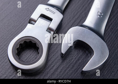 Nuovo cromato anello chiave con chiusura a scatto. Accessori per un meccanico su una tabella di officina. Sfondo scuro. Foto Stock