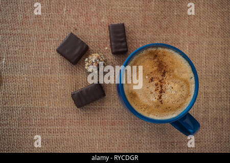 Caffè con latte e cannella in una tazza di colore blu con un po' di cioccolato Foto Stock