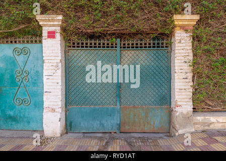 Sfondo di colore verde antico weathered grunge antique cancellata in ferro battuto con motivo geometrico ornamenti tra due mattoni bianchi colonne Foto Stock