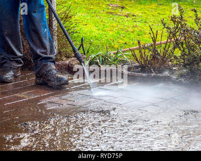 Pulire la pavimentazione del patio con un lavatore ad alta pressione l'uomo  sta usando l'acqua per pulire il percorso del giardino Foto stock - Alamy