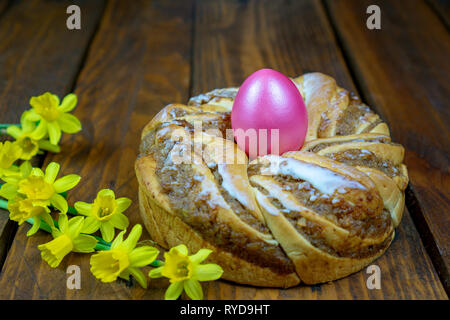 Tradizionale europea ghirlanda di Pasqua Osterkranz panetteria con noci una corona con un uovo di pasqua in medio e narcisi daffodil sul tavolo di legno Foto Stock