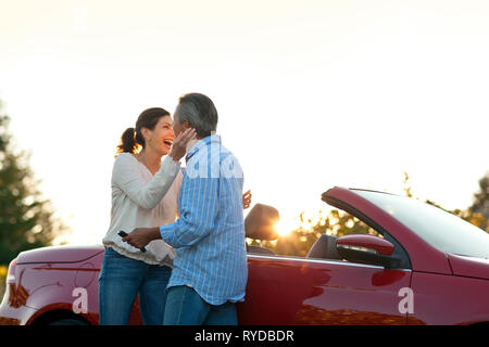 Coppia matura abbracciando accanto alla loro automobile. Foto Stock