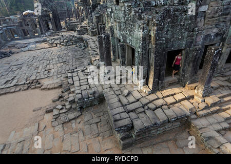 La madre e il figlio tra le antiche pareti di pietra al tempio Bayon ad Angkor in Siem Reap Foto Stock