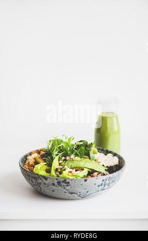 Una sana la cena o il pranzo. Vegan superbowl Buddha o ciotola con hummus, verdure, insalate fresche, fagioli, couscous e avocado e frullato verde in bottiglia Foto Stock