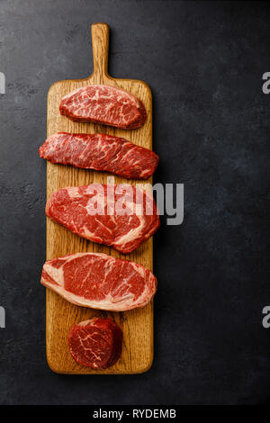 Varietà di materie Black Angus Prime bistecche di carne lama superiore, Denver, costola occhio, Controfiletto, filetto filetto mignon su tavola di legno su sfondo scuro Foto Stock