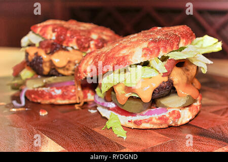 Vista ingrandita di due disordinati cheto hamburger su una tavola di legno. Foto Stock