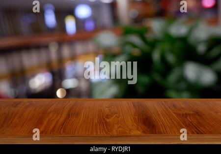 Vuoto in legno scuro tavolo di fronte abstract sfondo sfocato di ristorante, centro commerciale interno. può essere utilizzato per visualizzare o montage il tuo prodotto Foto Stock