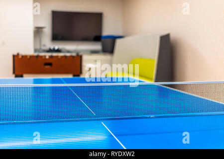 Primo piano di ping pong o ping pong net blu con colori vibranti isolato top sport gioco e nessuno in camera con biliardino e sullo schermo del televisore Foto Stock