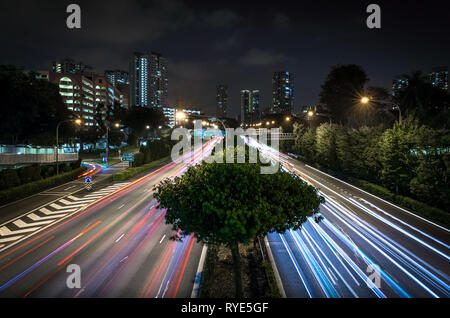 Skyline e auto faro e luce di coda percorsi su esposizione lunga strada di Singapore Foto Stock