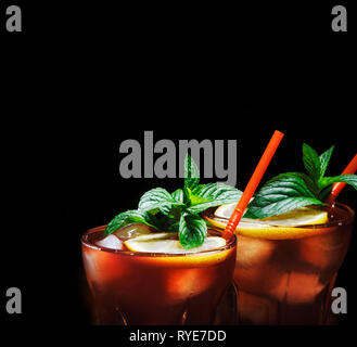 Cuba libre cocktail con ghiaccio, menta e limone su sfondo nero. Bevande alcoliche con il rum e la cola drink. Cocktail design menu sfondo. Foto Stock