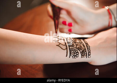 Processo di disegno di henna menhdi ornamento sulla donna di mano Foto Stock