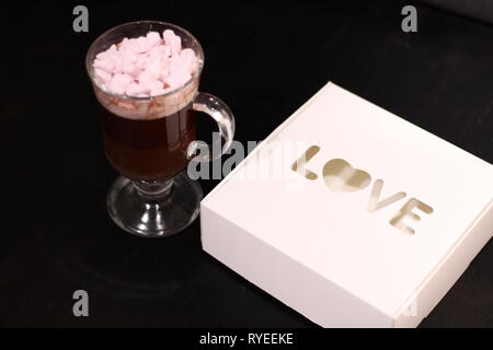 Bevanda calda in un bicchiere di vetro con rosa marshmallows Foto Stock