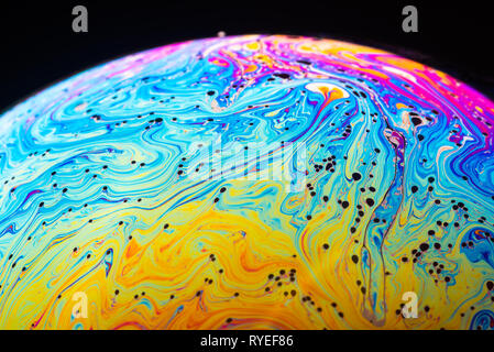 Abstract sfondo costituito da bolle di sapone che riflette la luce. Rainbow bolla di sapone su uno sfondo scuro. Foto Stock