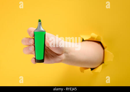 Mano che tiene un evidenziatore verde Foto Stock