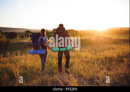 I viaggiatori con zaino camminando nel tramonto. Sagome di due escursionisti con zaini passeggiate al tramonto. Foto Stock