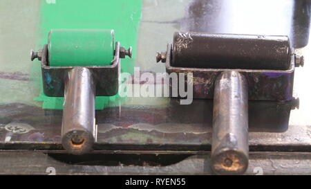 Un piccolo e grande rullo con l'inchiostro verde sulla piccola uno sulla parte superiore della tavola all'interno della vecchia stazione di stampa Foto Stock