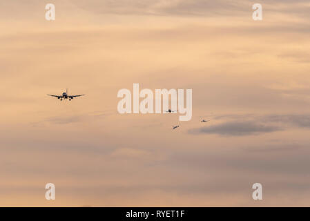 Coda di aerei in avvicinamento finale di atterrare all'Aeroporto di Londra Heathrow, London, Regno Unito all'alba. Gli aerei di linea di atterraggio. Finali di occupato per l'atterraggio all'aeroporto Foto Stock