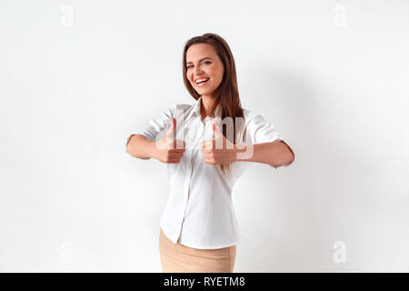 Freestyle. Donna in piedi isolato su bianco che mostra i pollici fino a ridere allegro Foto Stock