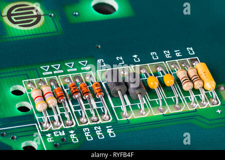 Induttori, condensatori, resistori e diodi sul PCB. Colorate di componenti elettronici di dettaglio. Scheda di circuiti verde. Interruttore a pulsante. Aprire la tastiera del computer. Foto Stock