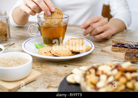 Tavolo in legno impostato per un dolce vegan colazione con fette di banana, frutta secca mista, vegan biscotti, fette di pane con marmellata e veg crema alla nocciola, m Foto Stock