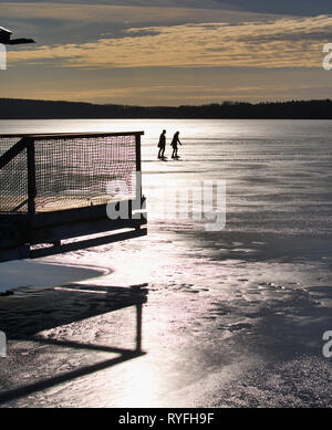 Due lunghe distanza pattinatori stagliano in condizioni di luce solare intensa sul lago Malaren, Sigtuna, Svezia e Scandinavia Foto Stock