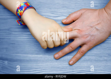 L'autismo consapevolezza dell'immagine. Padre tenendo la mano del suo bambino autistico Foto Stock
