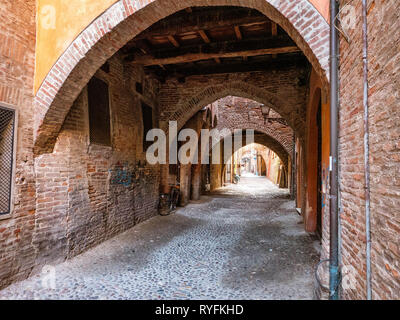 Stretta stradina laterale e archi nella città medievale di Ferrara, Italia Foto Stock