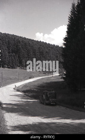 1930s, Cecoslovacchia, una vettura inglese dell'era parcheggiata su una ghiaia country road accanto a una foresta touring il paese in questo pre-ww2 era. Foto Stock