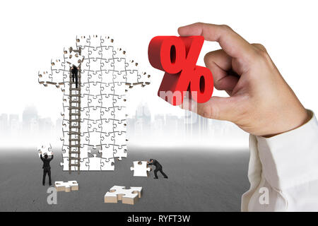 Mano azienda 3D rosso segno di percentuale con gli imprenditori costruzione freccia jigsaw puzzle e massa grigia cityscape sfondo Foto Stock