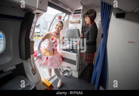 La ballerina Alice Kawalek da Scottish Ballet entra nel personaggio di imbarcarsi su un aereo come incontra Loganair hostess Lynne Smith (a destra) durante un photocall presso l'aeroporto di Glasgow davanti a loro Highland Fling Festival tour della "Wee Hansel e Gretel'. Foto Stock