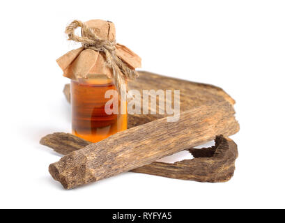 Legno di agar, chiamato anche aloeswood oudh. Con olio essenziale in bottiglia farmaceutica. Isolato su sfondo bianco. Foto Stock