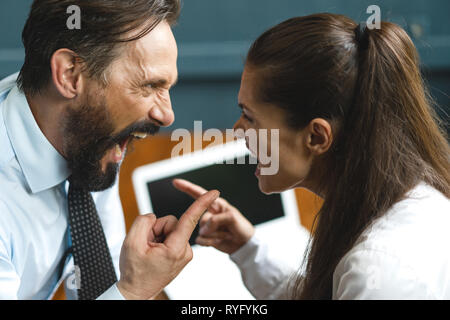 Colleghi di lavoro che sostengono e gridare a ciascun altro Foto Stock