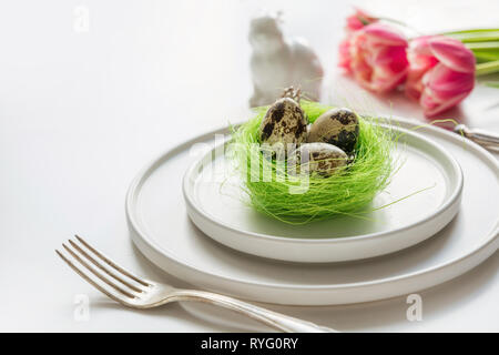 Pasqua messa in tavola con il colore rosa tulip su bianco. Primavera Romantica cena. Spazio per il testo. Foto Stock