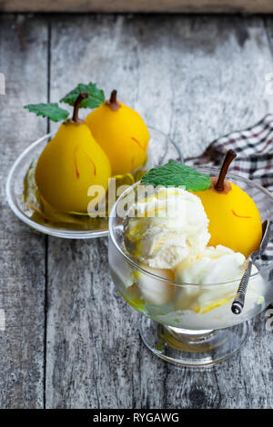 Dolce pera affogata con gelato alla vaniglia sul tavolo di legno Foto Stock
