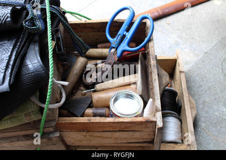 Le attrezzature utilizzate per le operazioni manuali di suola di calzatura sticthing memorizzato in un carrello di legno. Foto Stock