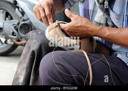 Processo di scarpa manuale Riparazione, suola e welt di fissaggio e di cucitura. Preso in Indonesia. Foto Stock