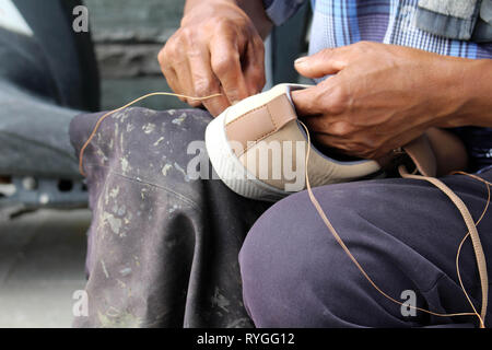 Processo di scarpa manuale Riparazione, suola e welt di fissaggio e di cucitura. Preso in Indonesia. Foto Stock