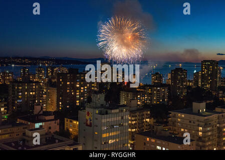 Fuochi d'artificio scoppio attraverso il cielo sopra Vancouver, British Columbia con lo skyline della città in primo piano. Foto Stock