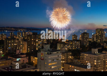 Fuochi d'artificio scoppio attraverso il cielo sopra Vancouver, British Columbia con lo skyline della città in primo piano. Foto Stock