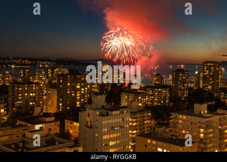 Fuochi d'artificio scoppio attraverso il cielo sopra Vancouver, British Columbia con lo skyline della città in primo piano. Foto Stock