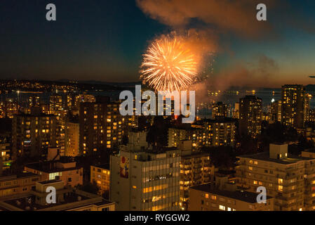 Fuochi d'artificio scoppio attraverso il cielo sopra Vancouver, British Columbia con lo skyline della città in primo piano. Foto Stock