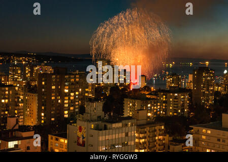 Fuochi d'artificio scoppio attraverso il cielo sopra Vancouver, British Columbia con lo skyline della città in primo piano. Foto Stock