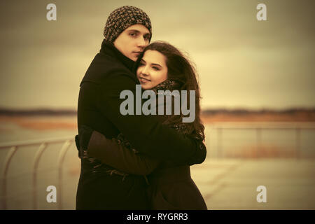 Felice coppia giovane in amore abbracciando outdoor elegante l uomo e la donna nel classico cappotti beanie e sciarpa Foto Stock