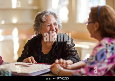 Due felici le donne anziane la riproduzione di un gioco di bordo insieme ad un tavolo. Foto Stock