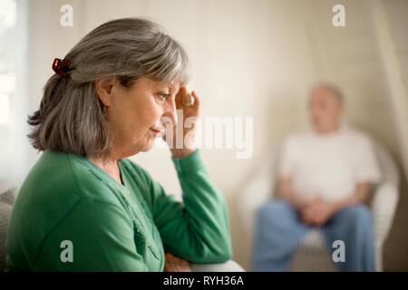 Interessato senior donna seduta in una stanza con il marito. Foto Stock