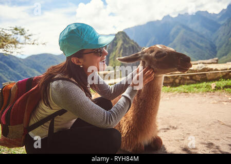 Donna che gioca con la lama il Machu Picchu sfondo Foto Stock